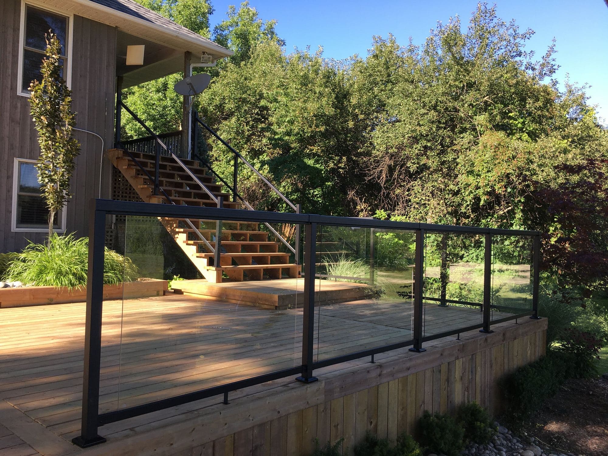 Wood deck with glass railing beside a brick home